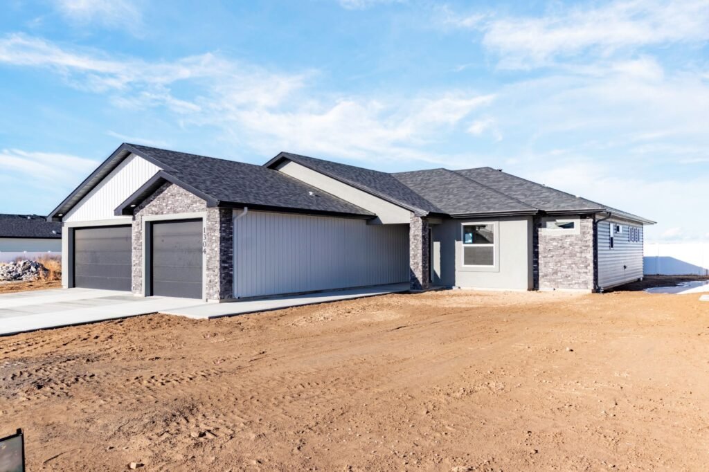 New single-story home with gray ASCEND composite board and batten siding, stacked stone accents, and black aluminum soffit, fascia and gutters